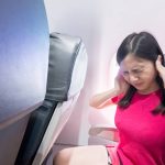 vrouw met oorpijn op het vliegtuig